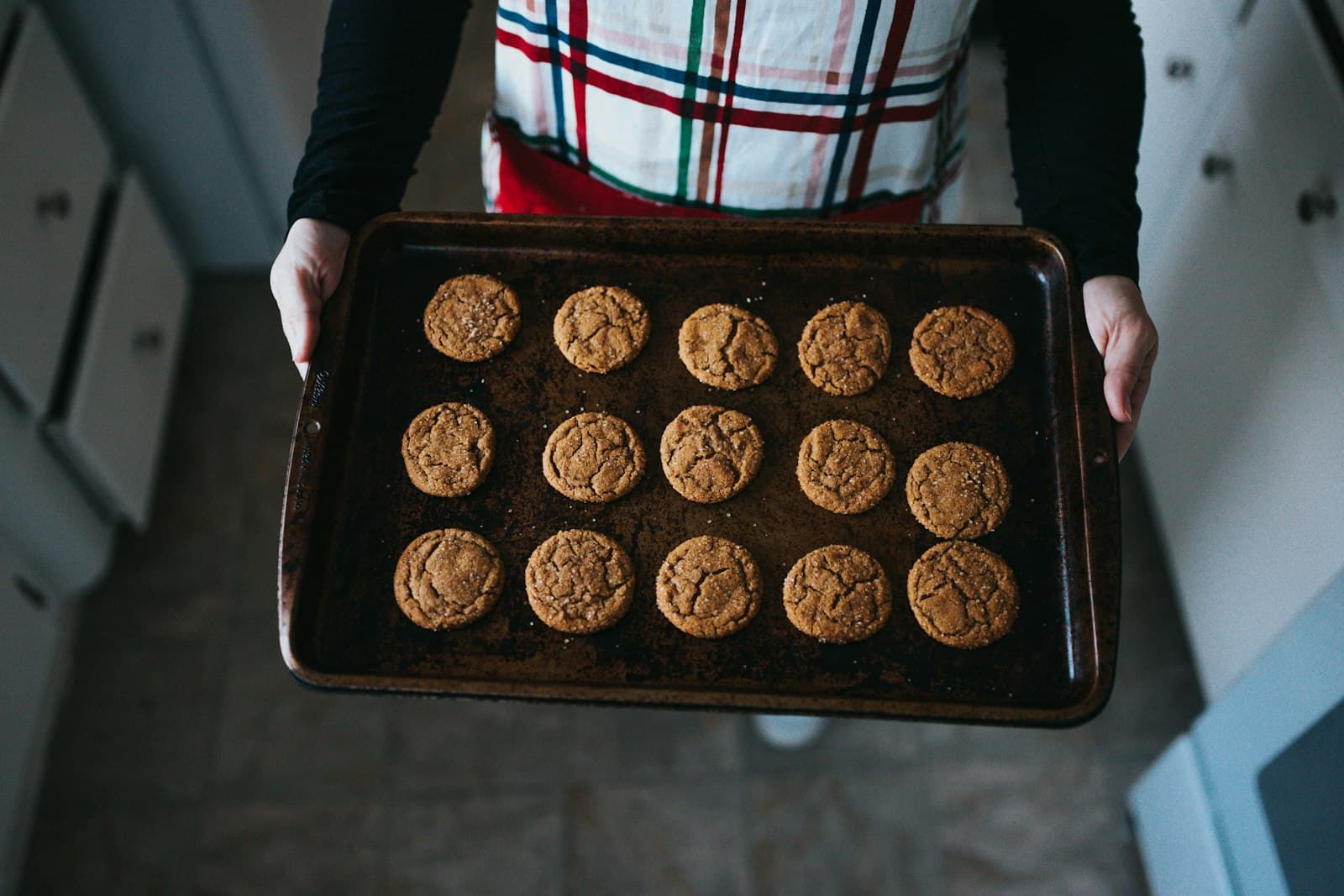 Person holding a tray of freshly baked cookies.